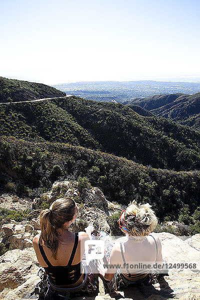 Zwei Bergsteigerinnen unterhalten sich über ihren Klettertag  während sie auf dem Lower Gibraltar Rock in Santa Barbara  Kalifornien  sitzen. Der Lower Gibraltar Rock bietet eine großartige Aussicht auf Santa Barbara und den Pazifischen Ozean.