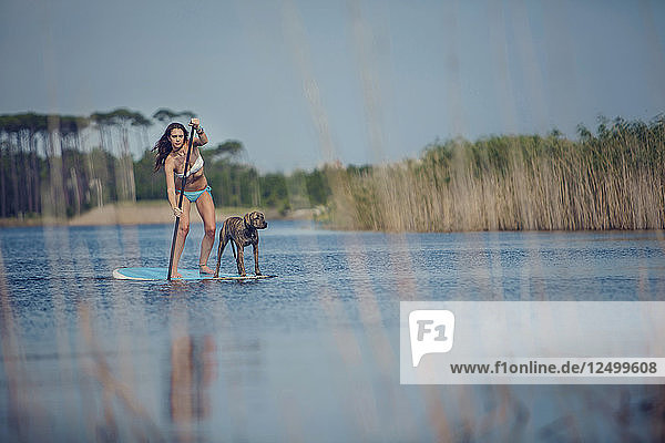 Eine junge Frau und ihr Hund fahren auf einem Stand Up Paddleboard auf einem See in Grayton Beach Florida.