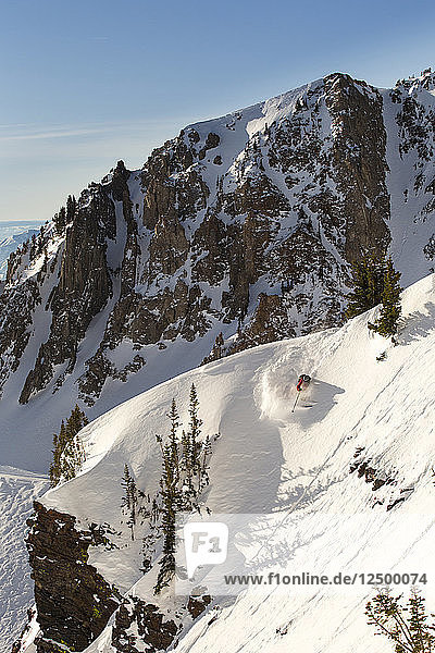 Extreme skier skiing down slope in extreme mountain terrain