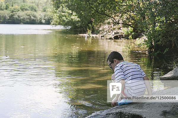 Boy plays by a lake.