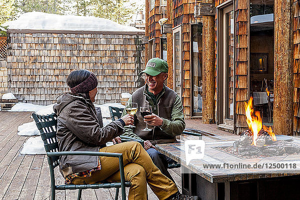 Couple toasting one another outside by a firepit at the lodge
