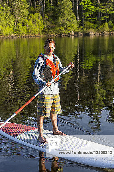 A Man Paddleboarding On Long Pond Near Greenville Maine