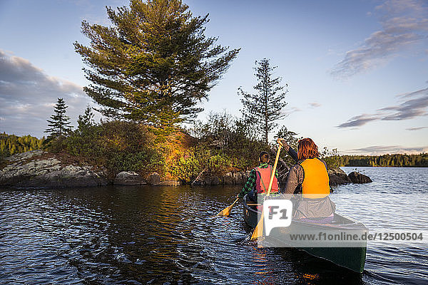 Ein junges Paar paddelt ein Kanu auf Long Pond in Maine's North Woods in der Nähe von Greenville,  Maine
