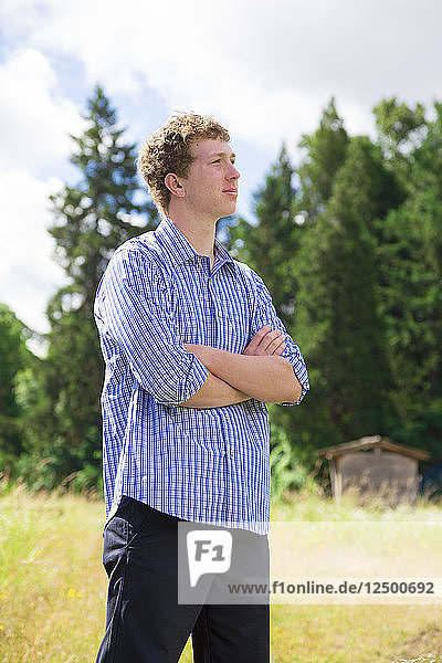 Young adult male poses for a lifestyle high school senior portrait outdoors at a natural park in Oregon.