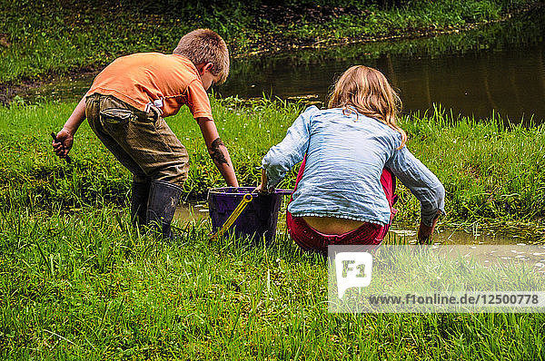 Ein Junge und ein Mädchen erkunden den Rand eines Teiches in Oxford OH