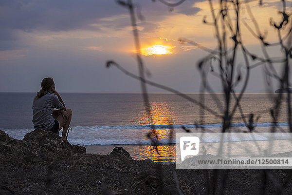 Frau betrachtet den Sonnenuntergang im Meer.West Sumbawa.Indonesien.