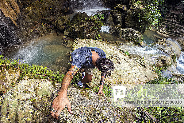 Mann klettert in der Nähe von Wasserfällen und Pools auf Java