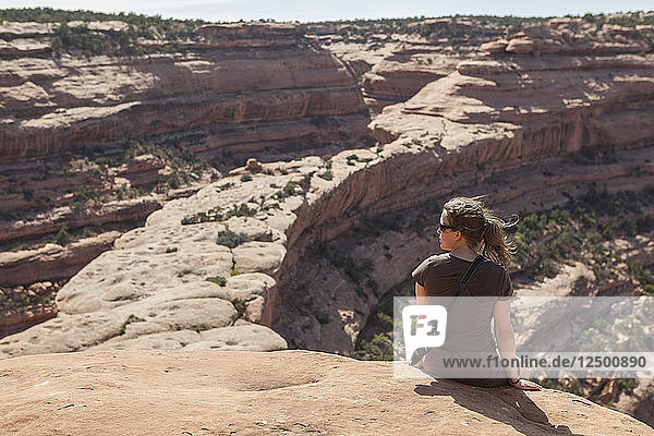 Eine Frau sitzt auf dem Grat  der zur Ruine The Citadel im Road Canyon  Cedar Mesa  Utah  führt.
