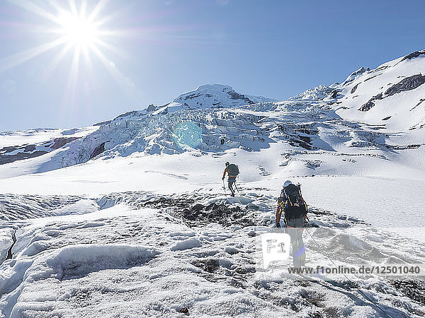 Two Climbers Hiking Toward The North Ridge Of Mount Baker In Washington  Usa