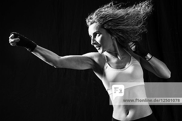 Action Shot einer weiblichen Boxerin mit Handpackungen  die mit den Fäusten zuschlägt