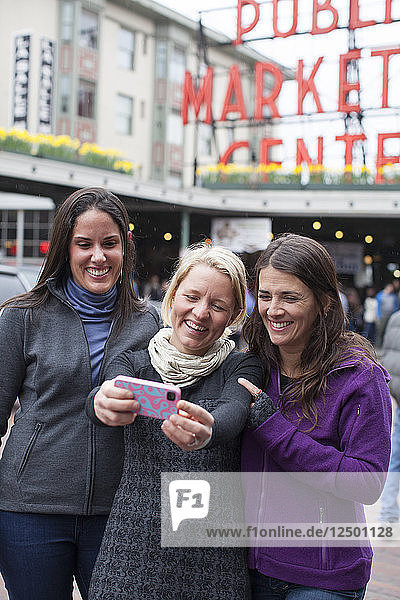 Die Freundinnen Brooke LaFave  Katie Cox und Suzanne Waldrup posieren für ein Selfie vor dem Pike Place Market in der Innenstadt von Seattle.
