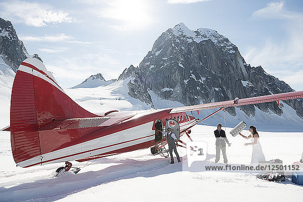 Bride and groom getting married next to a ski plane on a glacier in Denali National Park.
