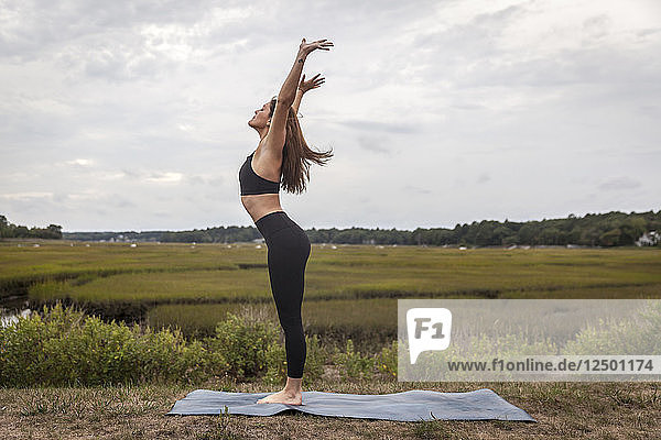 Frau über eine Vorwärtsfalte Vinyasa Flow draußen auf einer Yogamatte zu tun