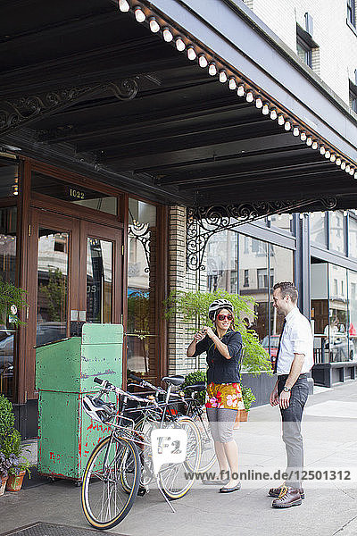 Ein Hoteldiener leiht einer Frau ein Fahrrad.