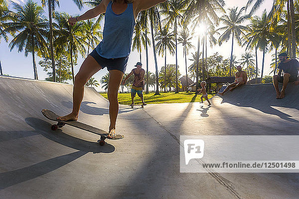 Menschen Skateboarding in Skate-Rampe unter Palmen