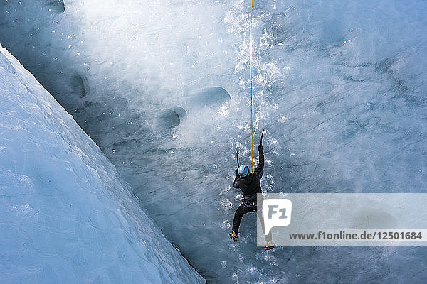 Mann klettert auf steilem Gletschereis am Gletscher Gigjokull. Südisland.