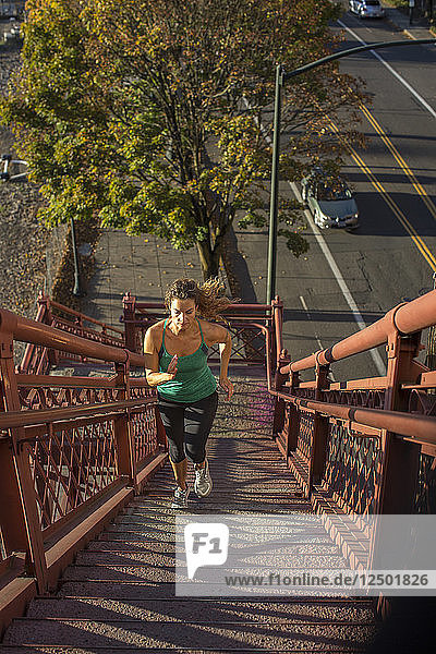 An adult woman running up the stairs of the Broadway Bridge in Portland  Oregon.