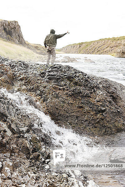Man casting beside a small hotspring while flyfishing on the river Nor??ur?°  Iceland.