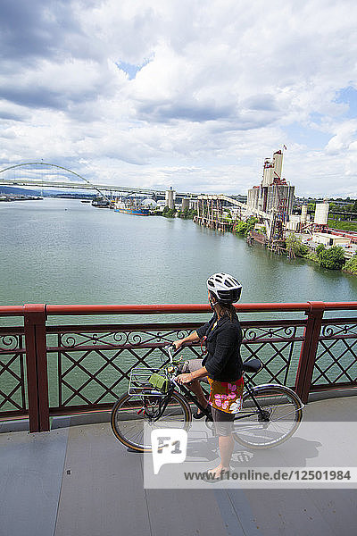 Eine Frau fährt über die Broadway Bridge in Portland  Oregon. Ein Blick auf die Stadt ist gleich dahinter.