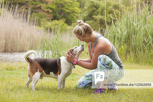 Woman petting beagle outside on grass in park