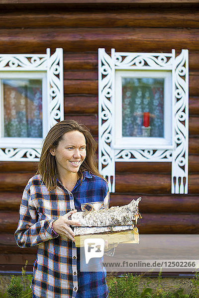 Lächelnde Frau hält Brennholz