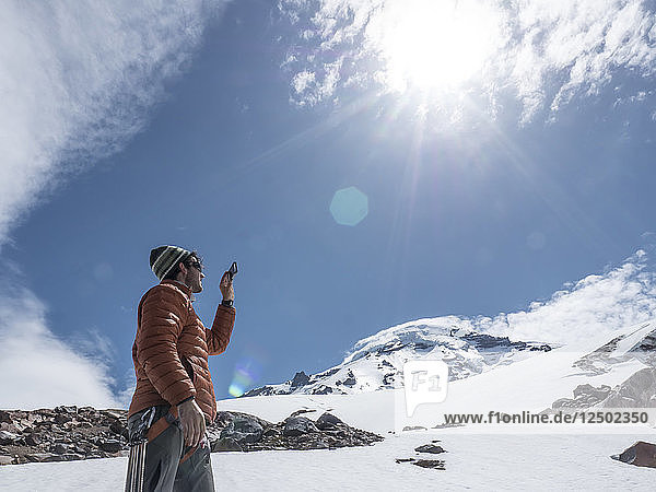A Man Taking Picture With His Phone While Hiking On Mount Baker