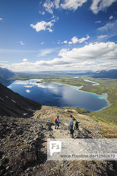 Two Hikers Sliding Down The Rocky Landscape Above Kathleen Lake In Yukon