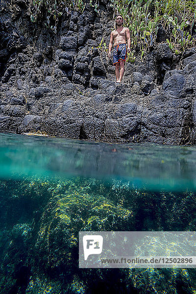 Man ready for jumping off cliff into the ocean. Summer fun lifestyle.