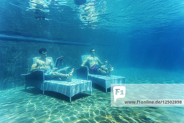 Two Men Lying On Bed Underwater In Pool
