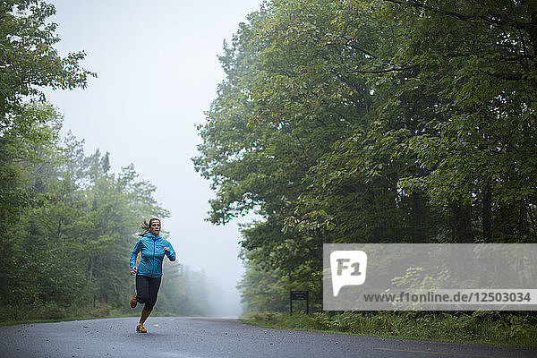 An adult woman running down a road in Big Bay State Park on Madeline Island  Wisconsin.
