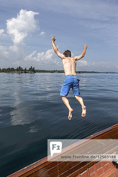 Mann springt von einem antiken Holzboot im Sankt-Lorenz-Strom