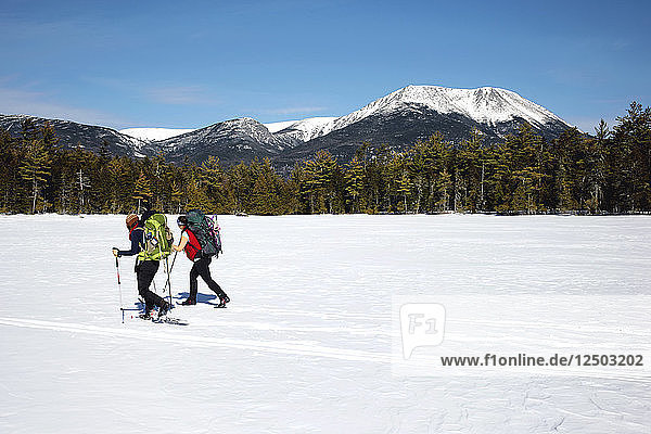 Two hikers cross a Frozen Pond in Baxter State Park in Maine.
