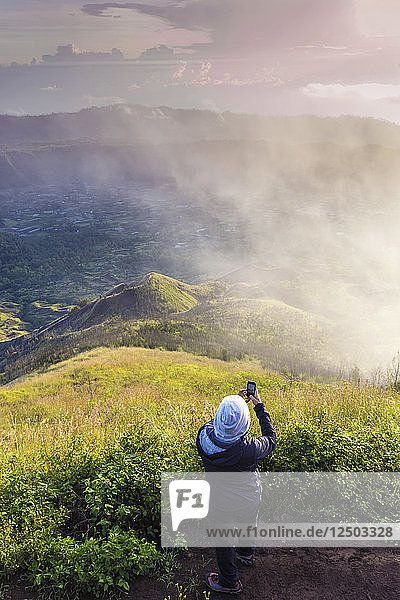 Wanderer  der auf dem Gipfel des Vulkans Batur  Bali  Indonesien  ein Foto mit dem Mobiltelefon macht