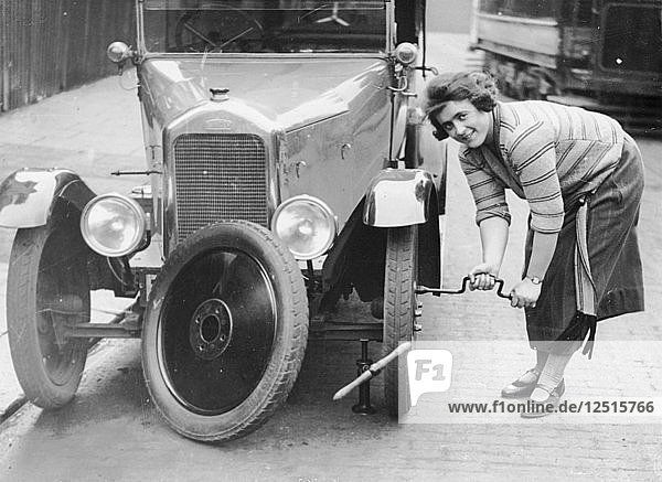 Ivy Cummings changing a tyre on a 1925 Singer 10/26 London c1925. Artist: Unknown