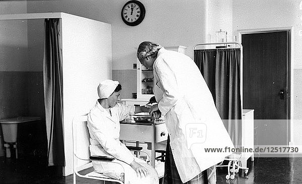 Der Rowntree-Arzt untersucht den Arm einer Mitarbeiterin  Rowntree-Fabrik  York  Yorkshire  1953. Künstler: Unbekannt