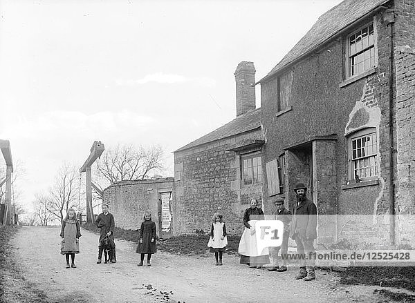 Familie vor ihrem Cottage mit der Kanalbrücke im Hintergrund  Uffington  Oxfordshire  1916. Künstler: Henry Taunt