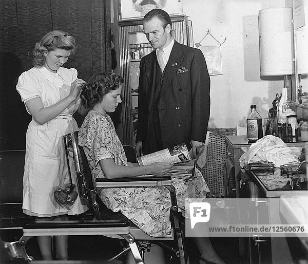 Ein Mädchen  das die Prüfung zur Friseurin vor einem männlichen Prüfer ablegt  Schweden  um 1940-1959. Künstler: Unbekannt