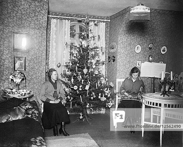 Zwei Frauen am Weihnachtsabend mit einem Weihnachtsbaum vor dem Fenster  Schweden  Anfang 1900. Künstler: Unbekannt