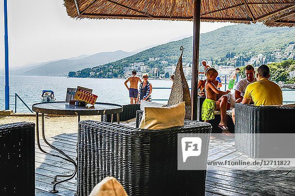 People sitting on the waterfront patio of a hotel bar in Opatija  Croatia.
