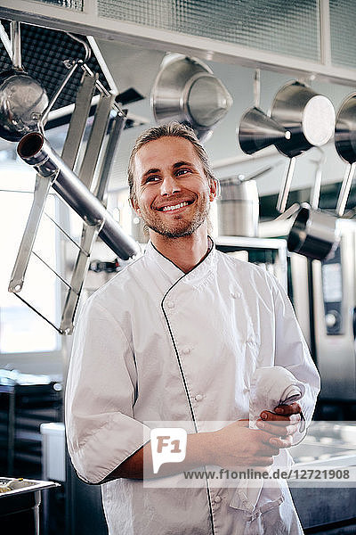Smiling young chef holding napkin in commercial kitchen