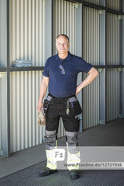 Portrait of confident senior male worker standing on warehouse entrance