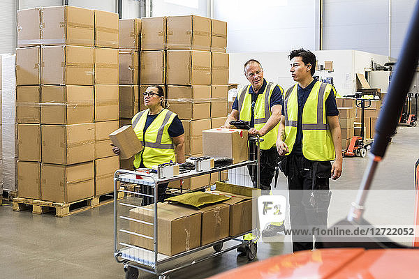 Multi-ethnic coworkers pushing cart at distribution warehouse
