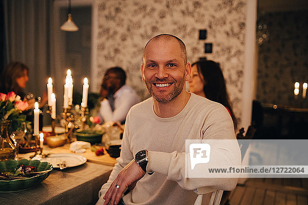 Portrait of mature man with friends at dining table in dinner party