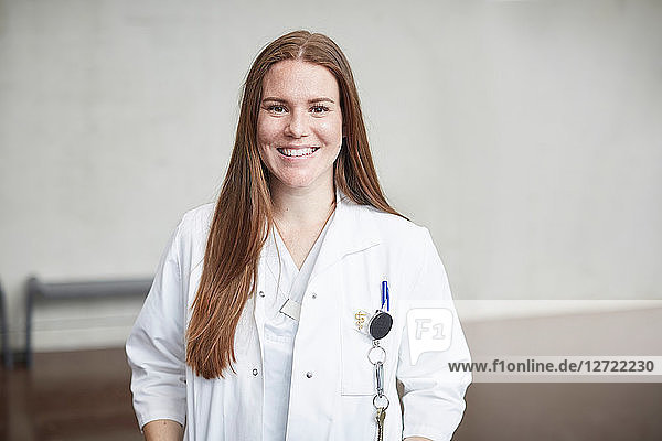 Portrait of smiling young female brunette doctor standing in corridor at hospital