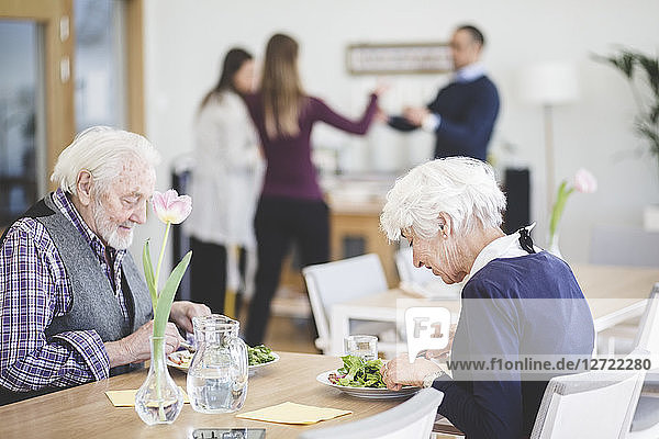 Senior couple eating lunch while at table in nursing home