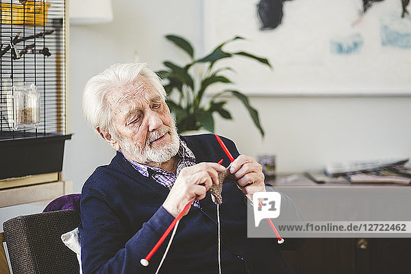 Senior man knitting while sitting in nursing home