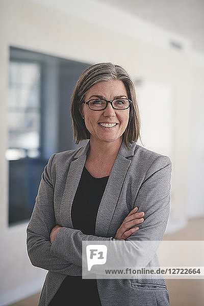 Portrait of confident mature businesswoman standing with arms crossed in office