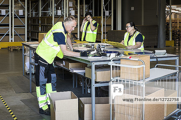 Multi-ethnic workers packing merchandise at distribution warehouse