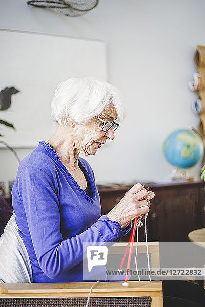 Senior woman knitting while sitting on chair in nursing home