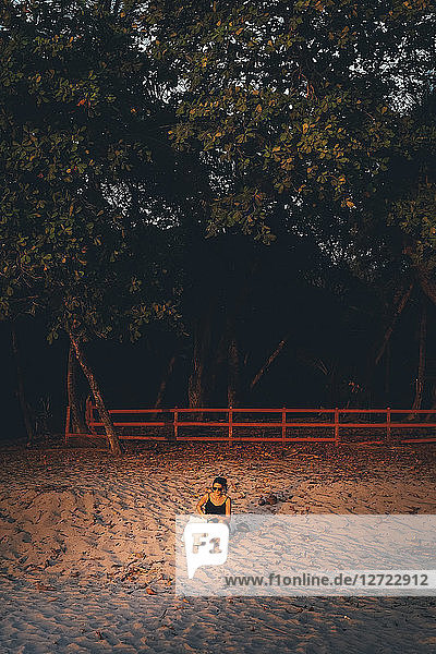 Woman relaxing on sand against trees at beach